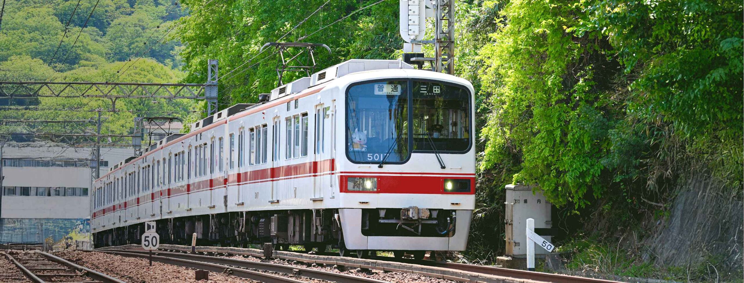 新開地行きの神戸電鉄の普通電車が街中の線路を走行している写真